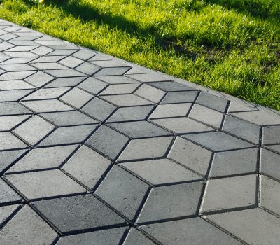The footpath in the park is paved with diamond shaped concrete tiles.