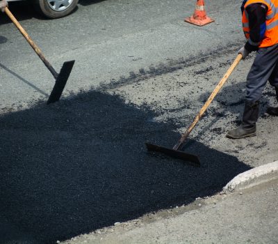 Road workers are paving. Section of road and wooden tools in hands.