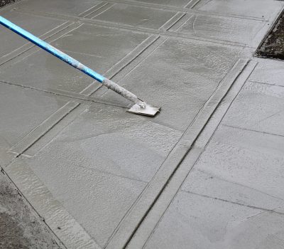A worker putting the finishing touches on a new concrete sidewalk by grooving in the expansion lines with a special tool